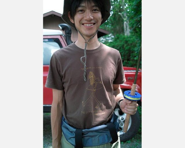 「The more you know… the less you need」と書かれたTシャツを着てテンカラ・ロッドを手にする横浜ストアの金子 達也。Photo: Daniel W. Galhardo