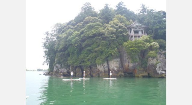 琵琶湖に浮かぶ沖ノ島まで友人に連れられて漕いで渡った。陸路からは行けない神社や海苔の養殖、琵琶鱒の漁をしている船を横目にたどり着いた島は、いい意味で時代に取り残された、時間が止まっているかのような佇まい。船で何かが届くと町内にアナウンスが入り、運ぶのを手伝える人を募って、みんなが集まってくる。木造の小学校、小さな畑や港、蛍光灯や五右衛門風呂、土間や引き戸のある家、桟橋から水に飛び込んで遊ぶ子供たち、昔は当たり前にあったものがとても新鮮に見えたことがちょっと寂しく感じたりもした。〈沖の島ツアーPUKAPUKA〉写真:白井 和夫
