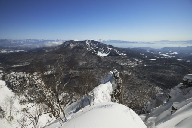 九頭龍山頂より戸隠スキー場、右に南アルプス、富士山を望む。手前から伸びる尾根から最後の下見をする2人。奥:狩野、手前:島田。写真:松尾憲二郎