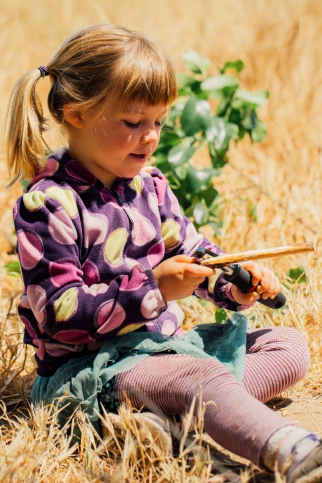 子供たちは木の棒を削るために、各自の技量によって野菜用ピーラーかナイフを選ぶ。彼らは鋭い道具を使う前に落ちた枝や棒を使って「血の輪」を作り、他の子供たちにその輪の外側が安全であるとわかるようにする。Photo: Kyle Sparks