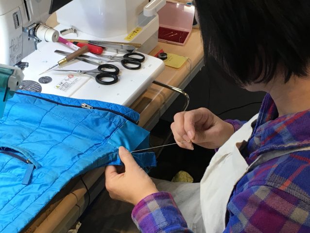 ハイロフト製品の裾の破れ修理。ミシンで縫う前に当て布をしつけする。
写真:パタゴニア日本支社