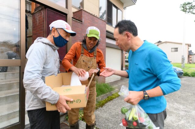 ご近所さんからいただいた嬉しいお裾分けを仲間と分け合う。 写真:下山 展弘