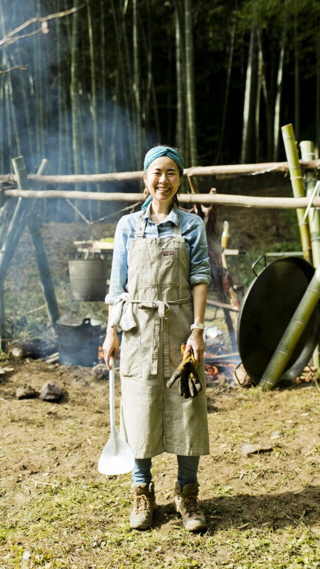 焚き火料理に欠かせないのは、ガンガン使っても直火で焦げてもへたらない、丈夫で使い勝手のいいワーク・エプロンだ。愛用の一枚を身に着けて。写真 : 五十嵐 一晴